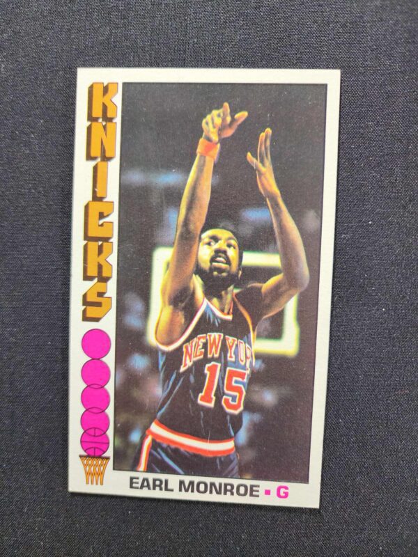 A card of earl monroe with his hands raised.