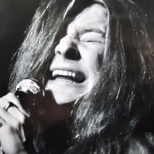 A woman with long hair is singing into a microphone.