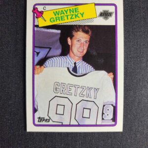 A card of wayne gretzky holding up his jersey.