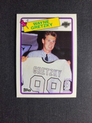 A card of wayne gretzky holding up his jersey.