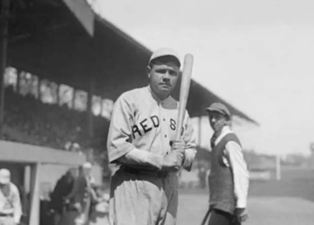 A baseball player holding a bat in front of an audience.