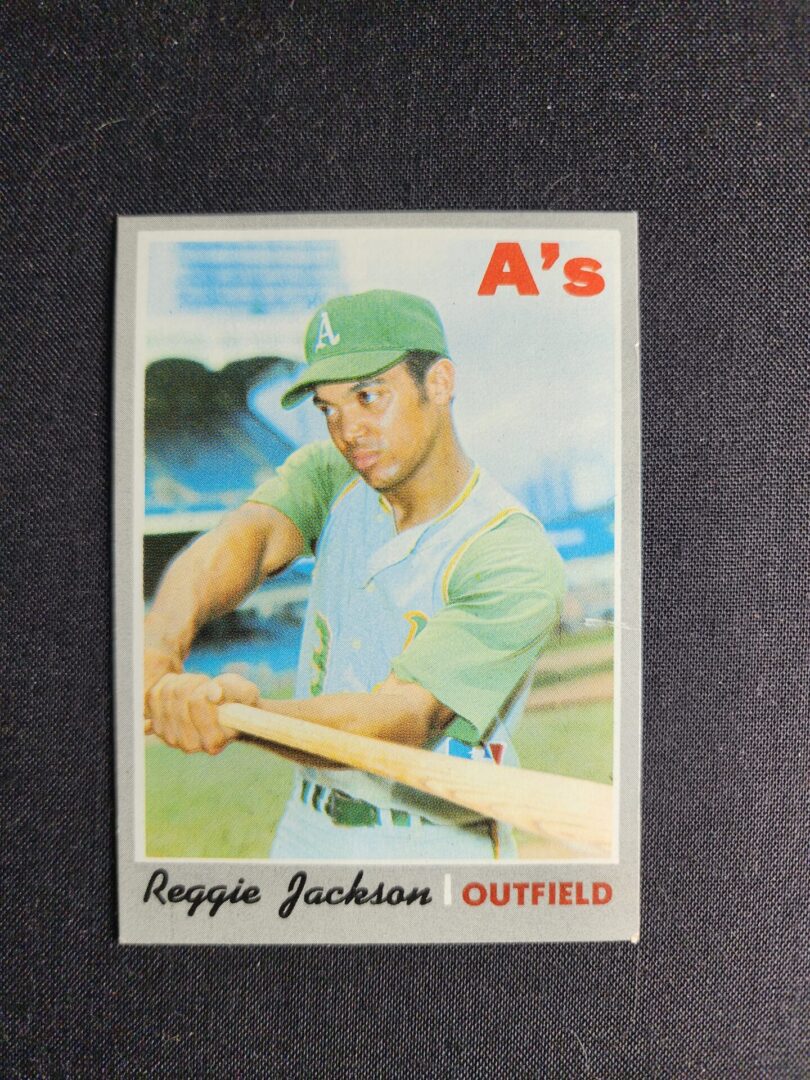 A baseball card of reggie jackson, the first baseman for the oakland athletics.