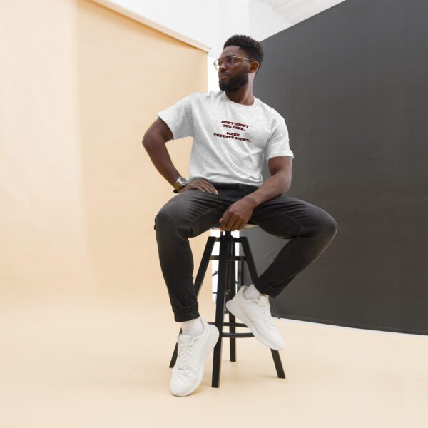 A man sitting on top of a stool in front of a wall.