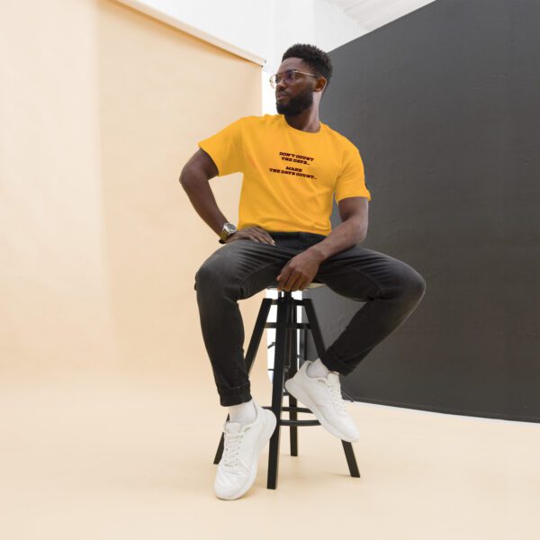 A man sitting on top of a stool wearing a yellow shirt.