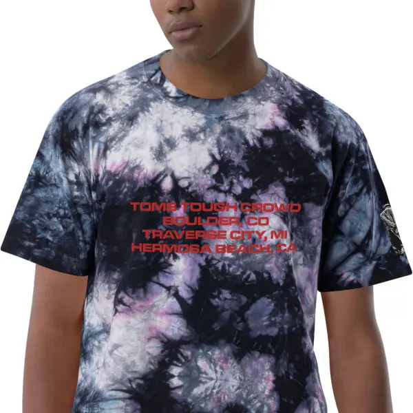 A man wearing a tie dye shirt with words on it.