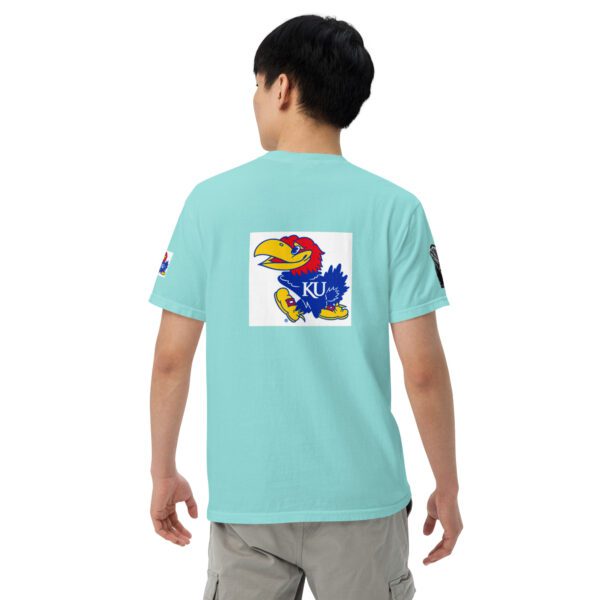 A boy wearing a light blue shirt with an image of the kansas jayhawks on it.