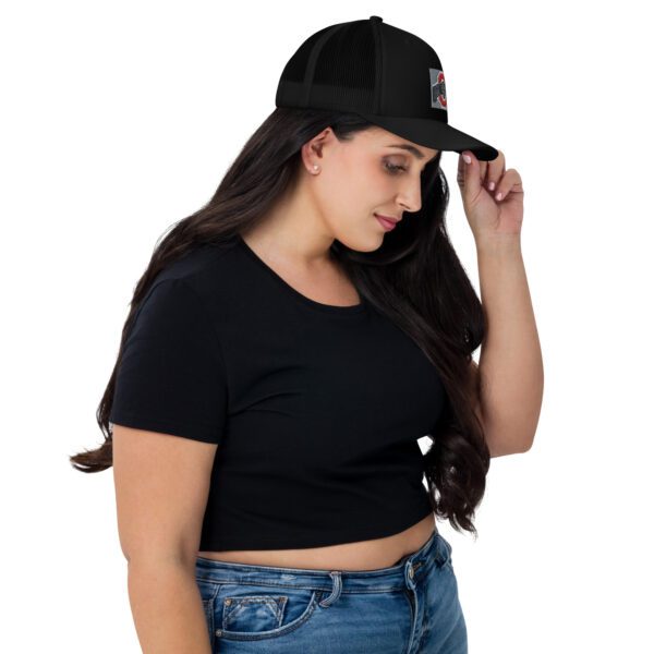 A woman wearing black shirt and jeans holding her hat.