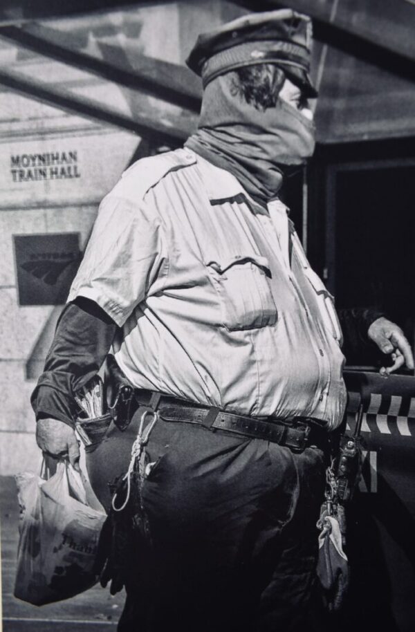 Man in uniform holding a grocery bag.