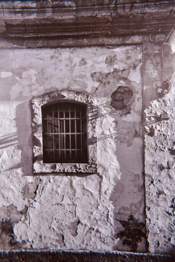 Barred window on weathered wall.