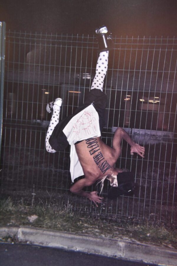 Person hanging upside down on fence.