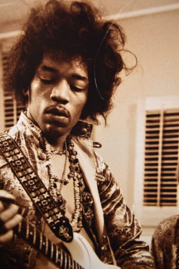 Jimi Hendrix playing guitar in sepia tone.