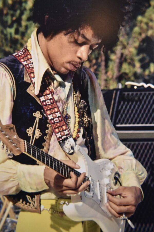 Jimi Hendrix playing a white guitar.