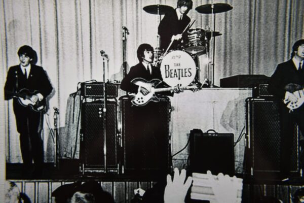 The Beatles performing live on stage.