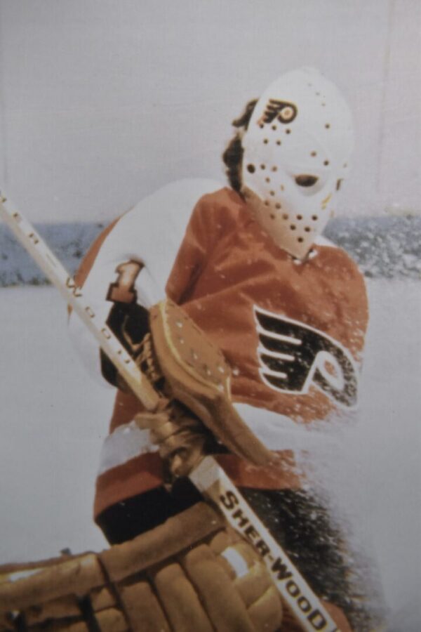 Hockey goalie in Flyers jersey with mask.