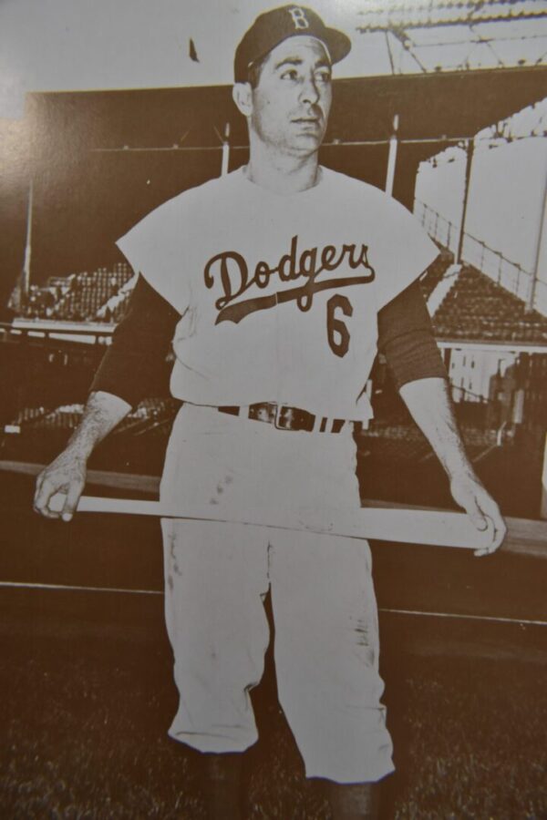 Baseball player in Dodgers uniform holding bat.