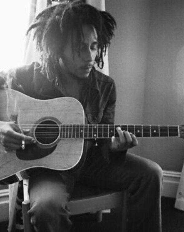 Bob Marley playing acoustic guitar.