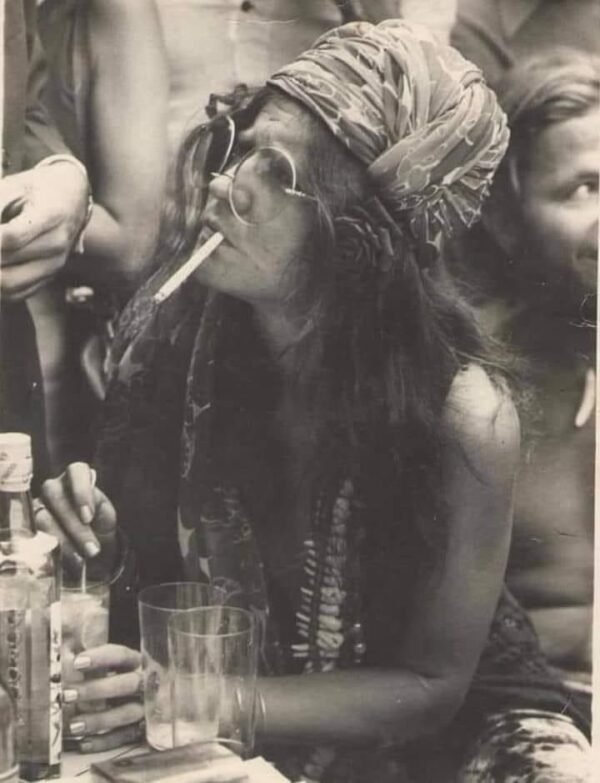 Woman with headband smoking and drinking.