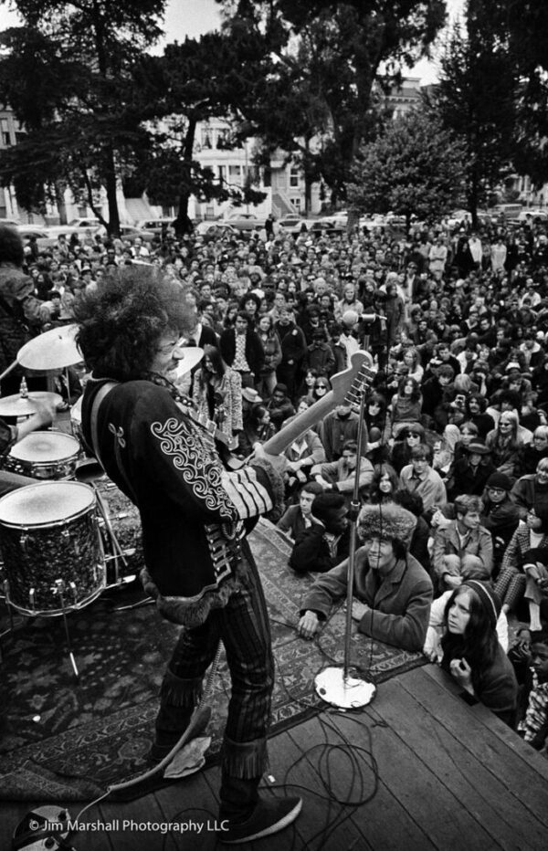 A musician plays guitar on stage for a crowd.